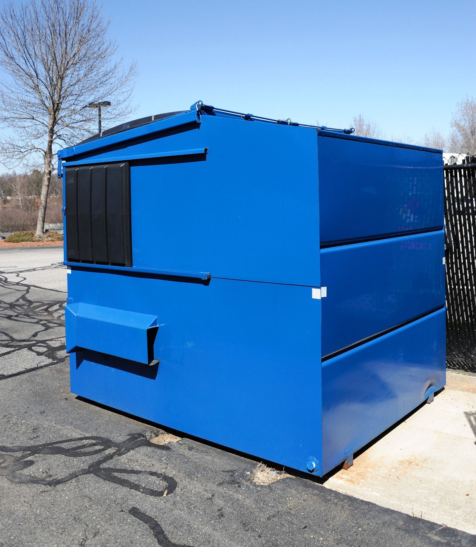 A blue dumpster is sitting on the side of the road