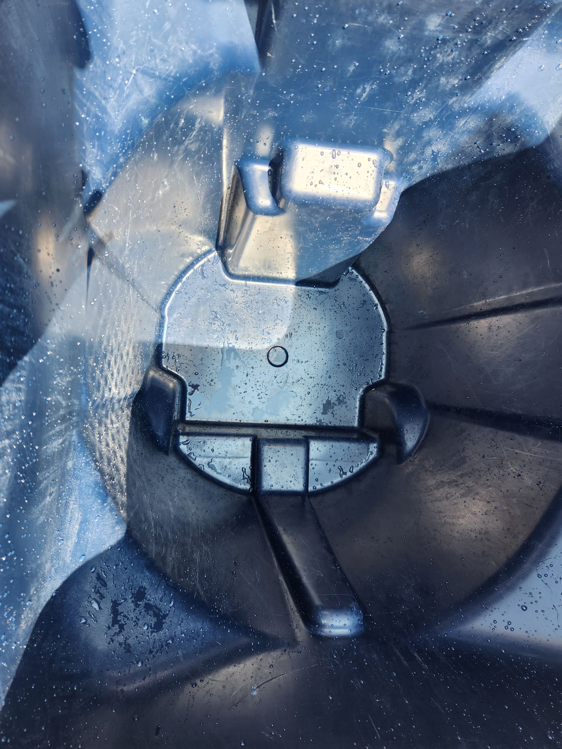 A man is putting trash into a trash can on the sidewalk.