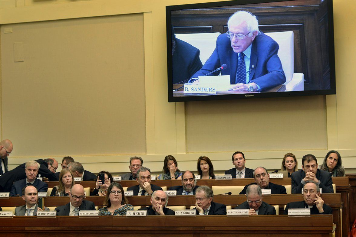 A group of people sitting in front of a large screen that says ' sanders ' on it