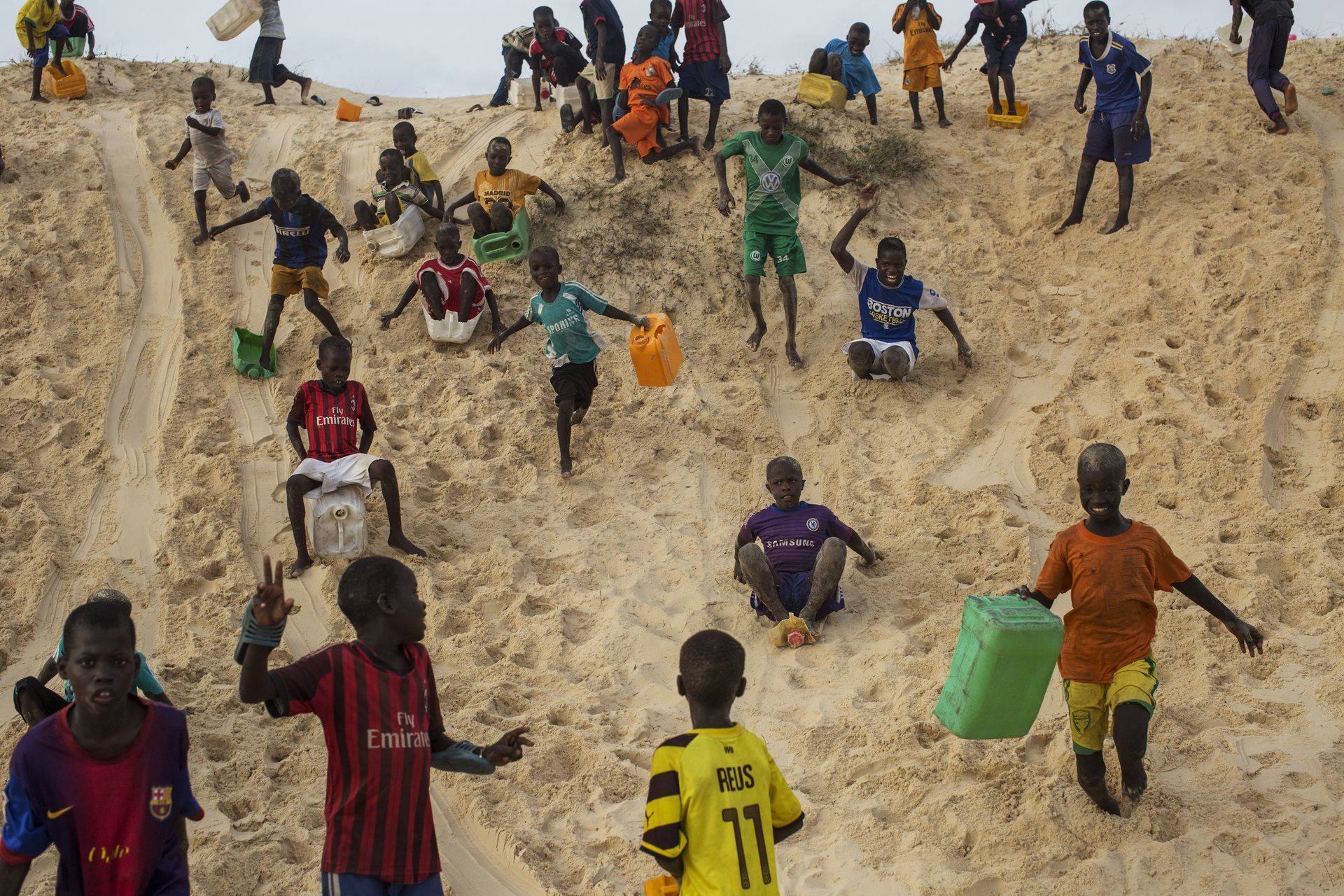 VII Foundation: Children walking, running, and sliding down a sand dune