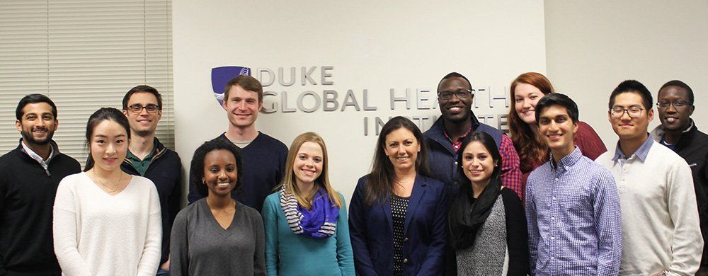 Duke Global Health Institute employees standing in front of the Duke logo