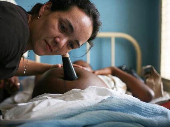 Women with Duke Global Health institute listening for the heart beat of a baby on a pregnant women's stomach