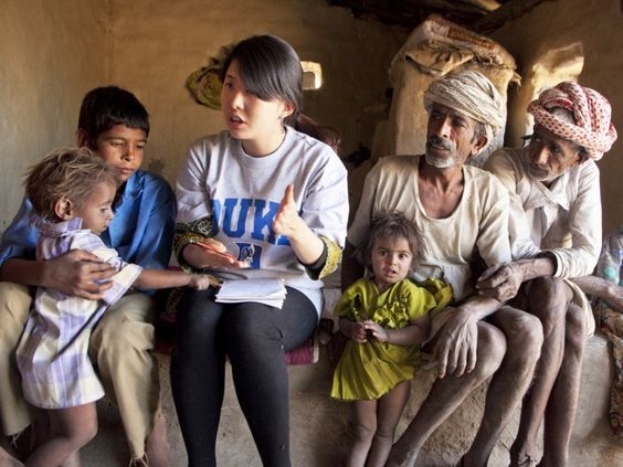 A student from Duke Global health Institute walking with men, women, and children of a village