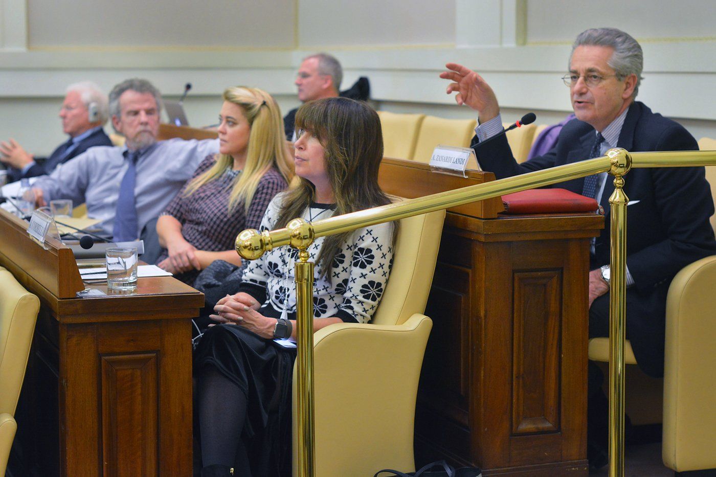 A group of people are sitting in a row in a council chamber.