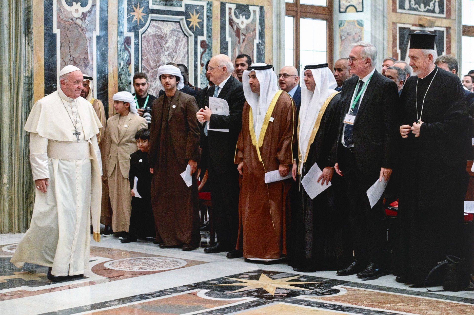 Pope Francis walking in front of a group of men
