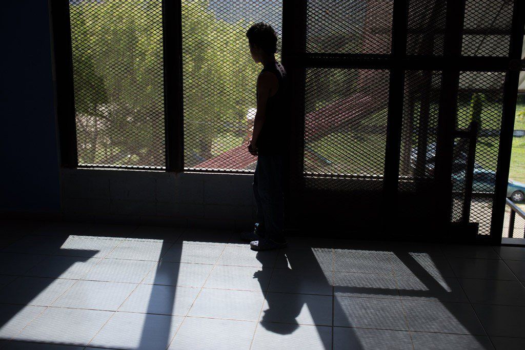 A child looks out a screened-in area at a school.