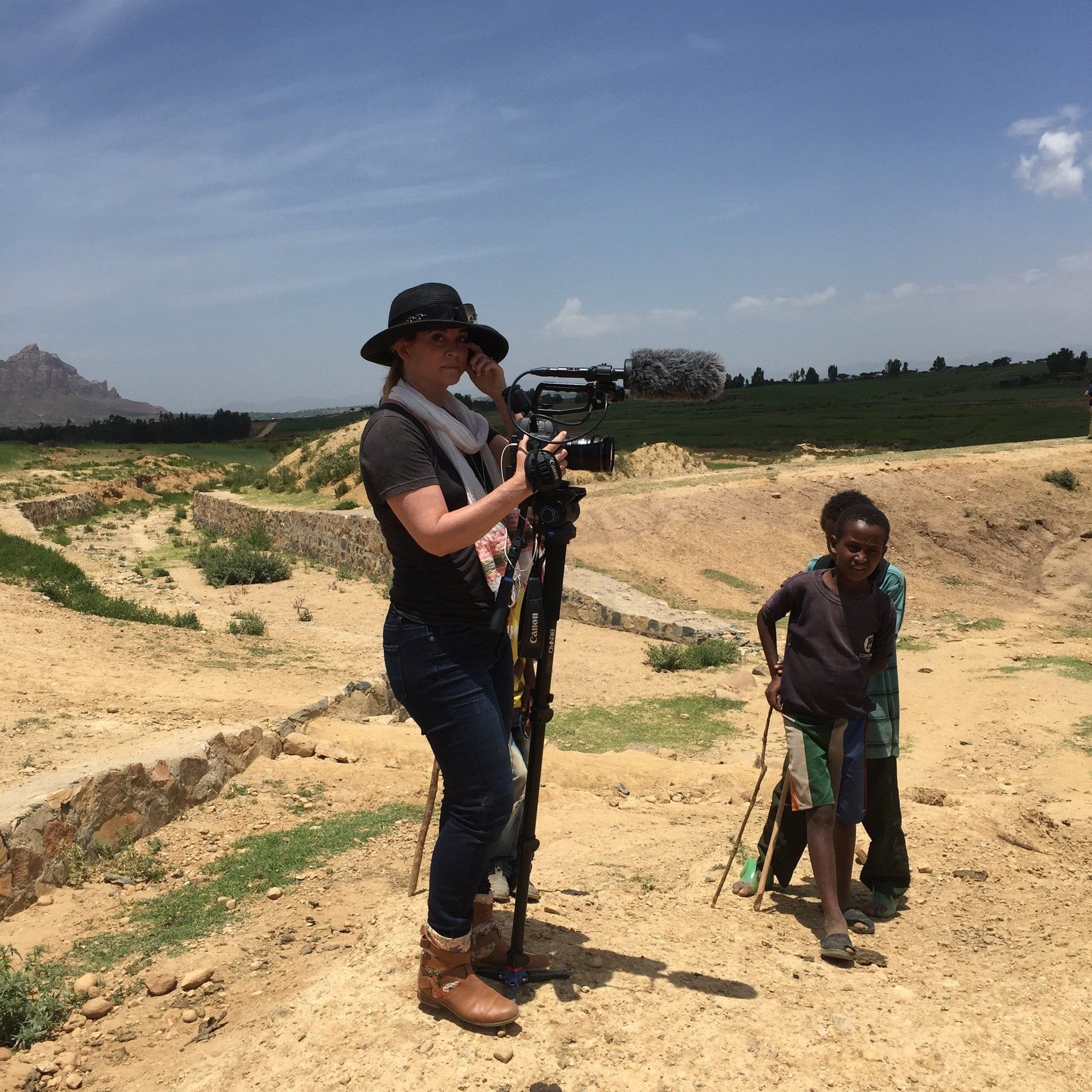Camera operator filming rural life with a child nearby