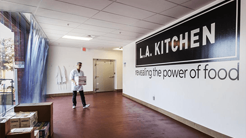 LA Kitchen student walking near the LA Kitchen logo