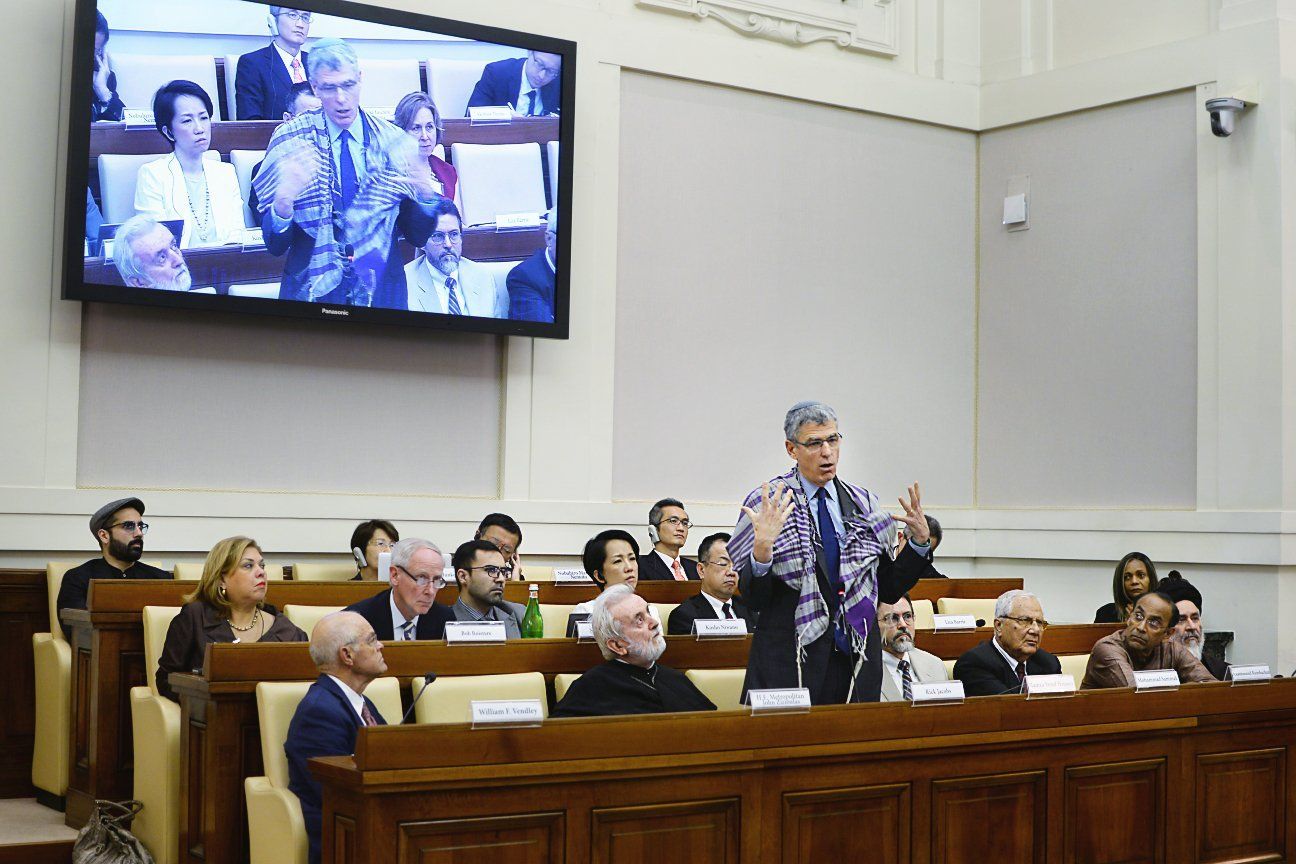 Jennifer Gross and a group of people listening to a speaker at a Ethics in Action 3: Migrants and refugees