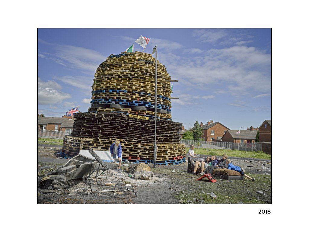 The Peace Project: A structure made out of pallets with flags on top with kids sitting on a couch near by