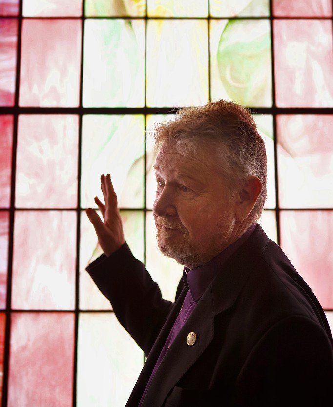 A man standing in front of a stained glass window