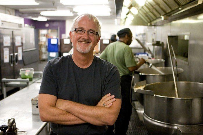 LA Kitchen chef posing for a picture with students working in the background