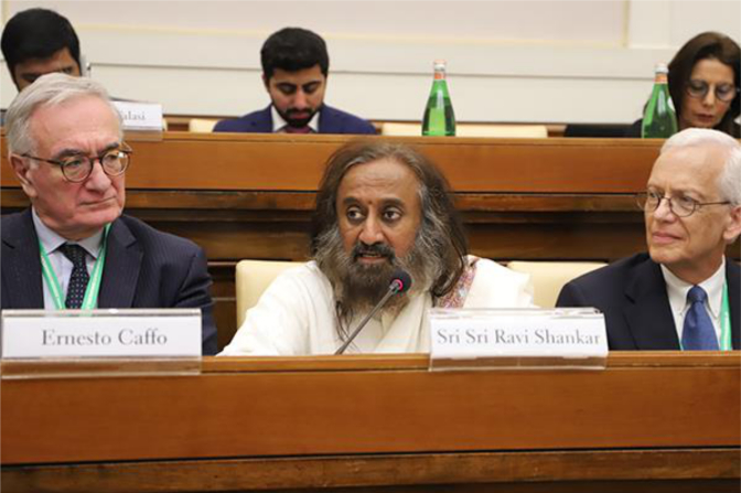 A man with a beard is sitting at a desk with a name tag that says ernesto caffe