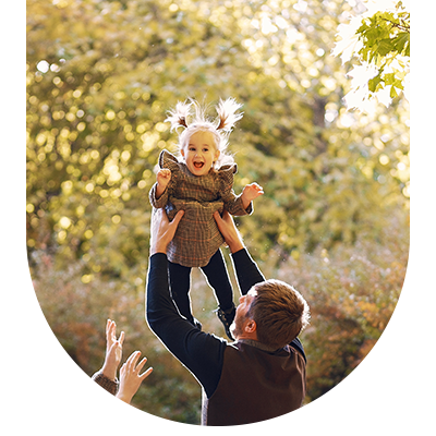 Man lifting child in a park, symbolising comprehensive family dental care at Hampstead Clinic