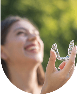 dy smiling and holding Invisalign, showcasing orthodontic treatment at Hampstead Clinic