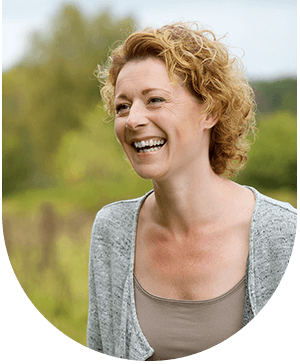 Smiling woman in a field, representing enhanced bone health for successful dental implants at Hampstead Clinic