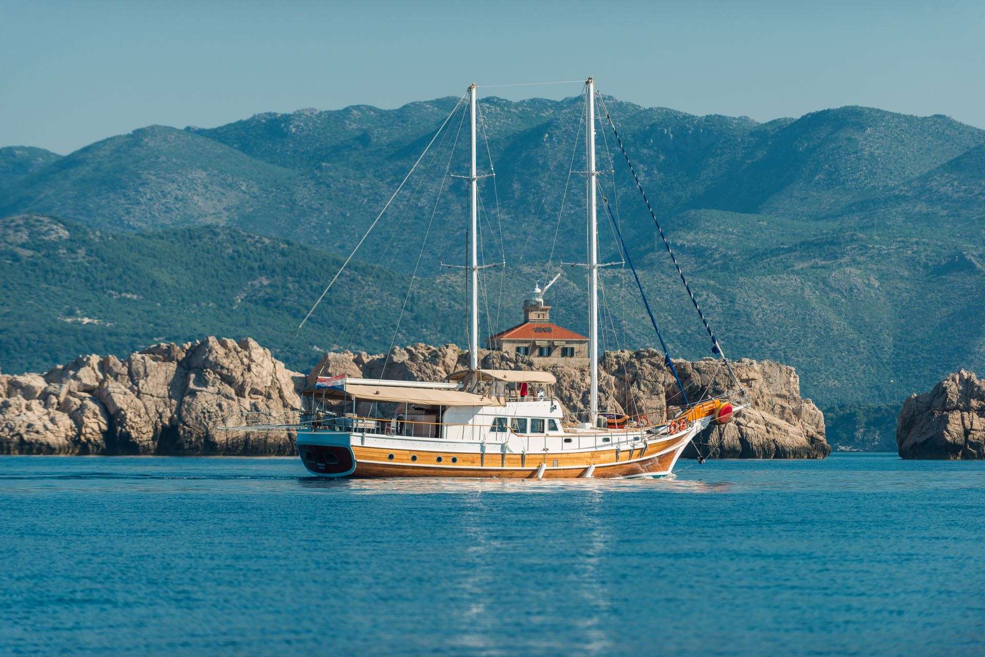 Een boot drijft in de oceaan met bergen op de achtergrond