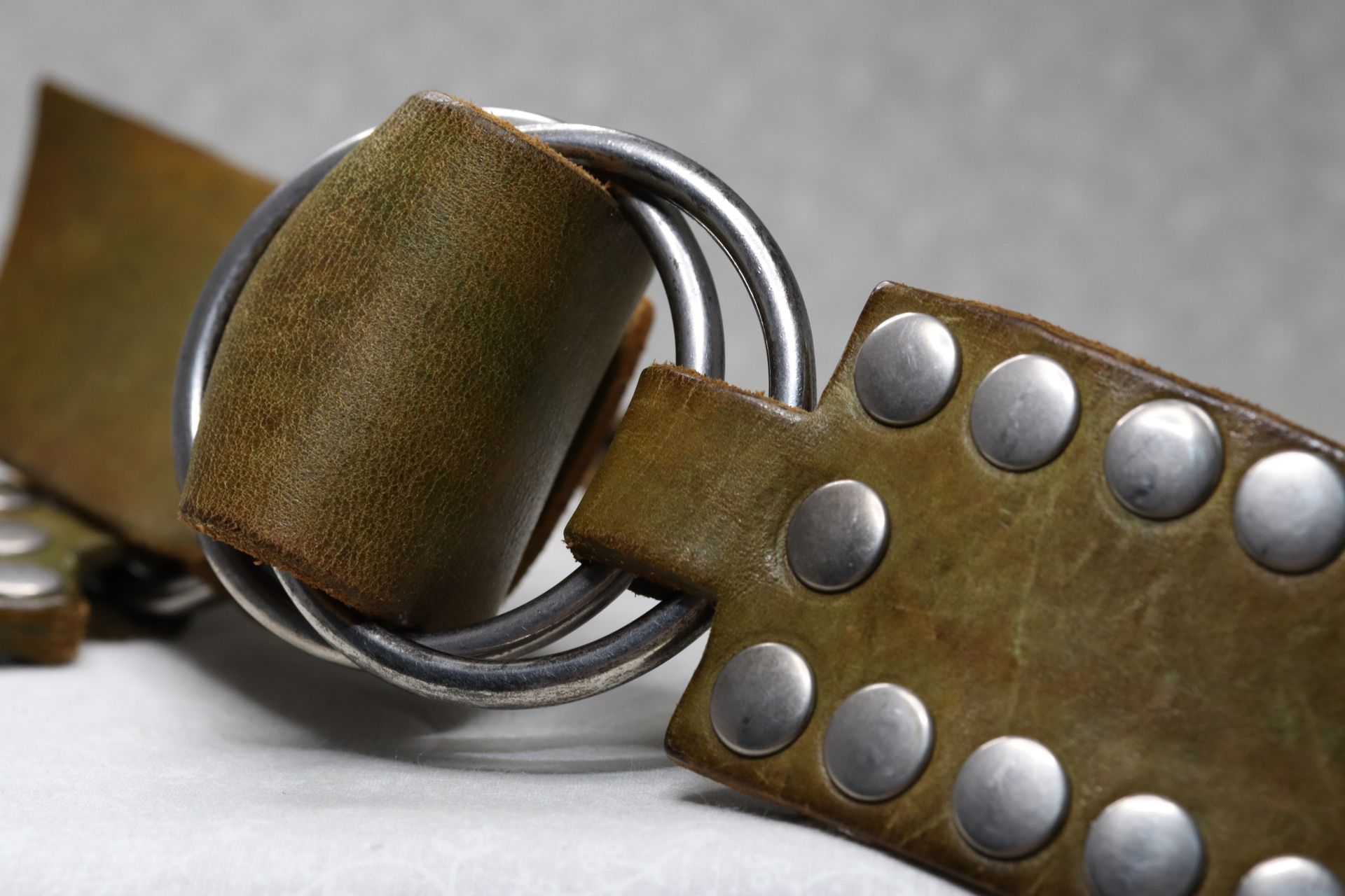 A brown leather belt with studs and a metal buckle