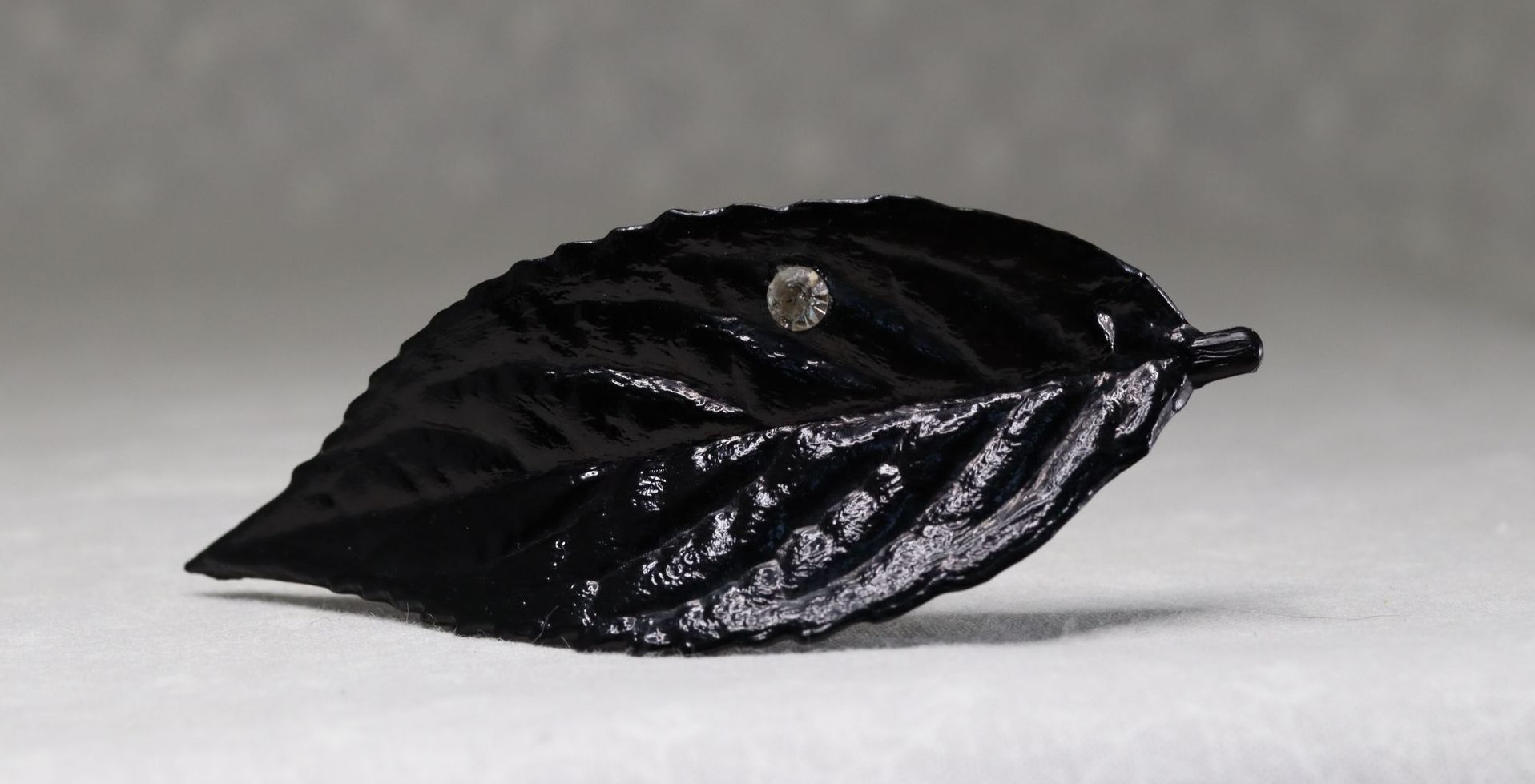 A black leaf is sitting on a white surface.