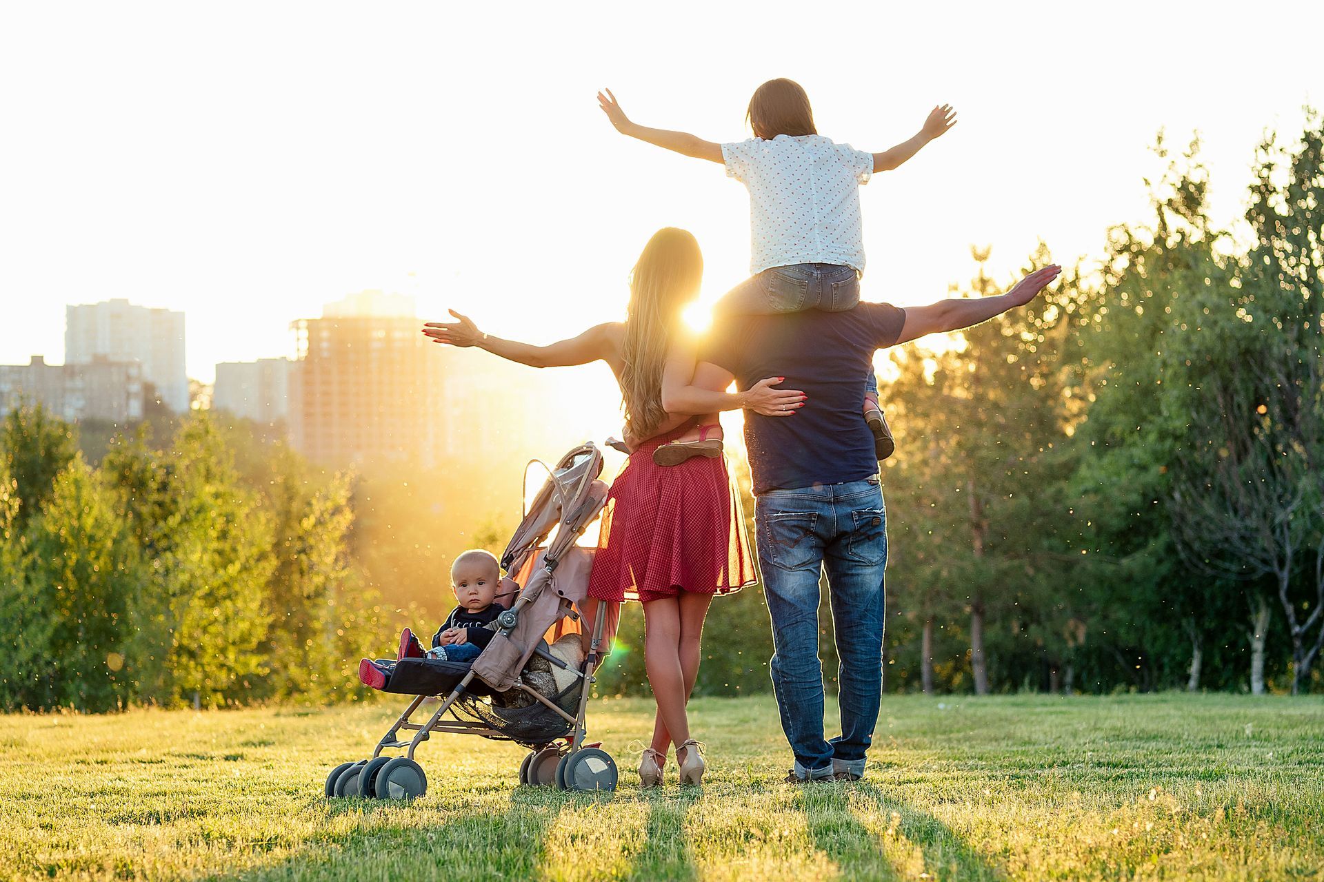 a family is standing in a park with a baby in a stroller .