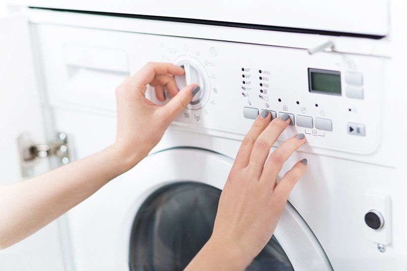 Woman's Hand Turning On The Washing Machine — Chicago, Il — A-Appliance Xperts Inc.