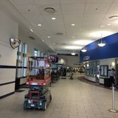 A long hallway with a red lift, likely in a car dealership. White ceiling, blue accent wall, and bright lighting.