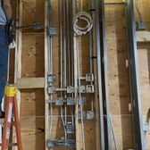 An attic view with wooden beams above a concrete floor. A metal box and flexible ductwork are in the center.