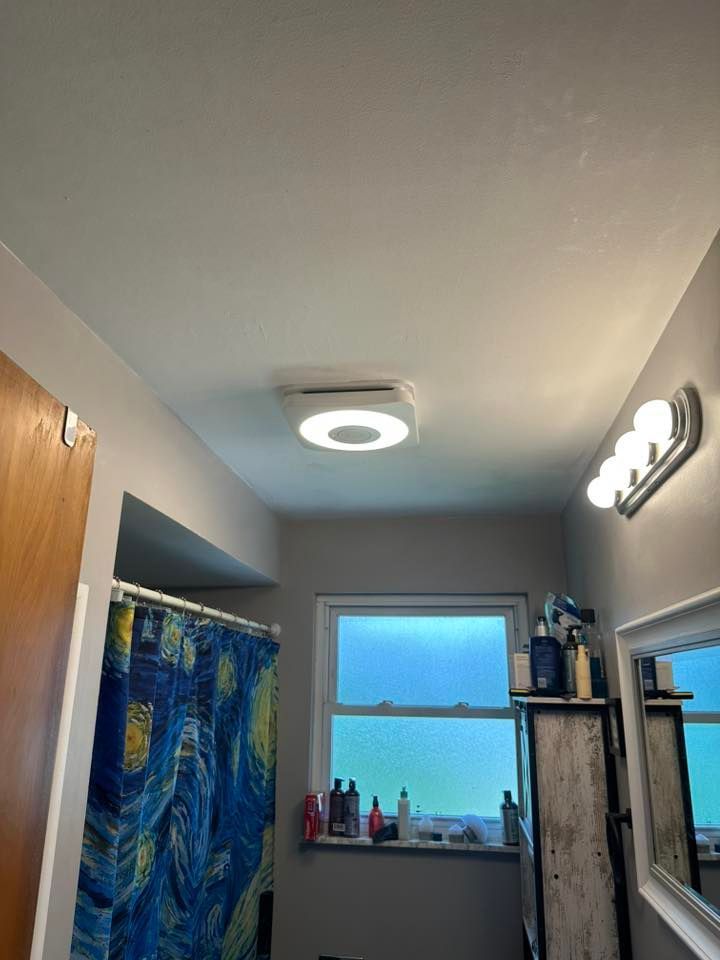 Bathroom with a round ceiling light, a window, and a vanity with a mirror. A shower curtain is visible on the left.