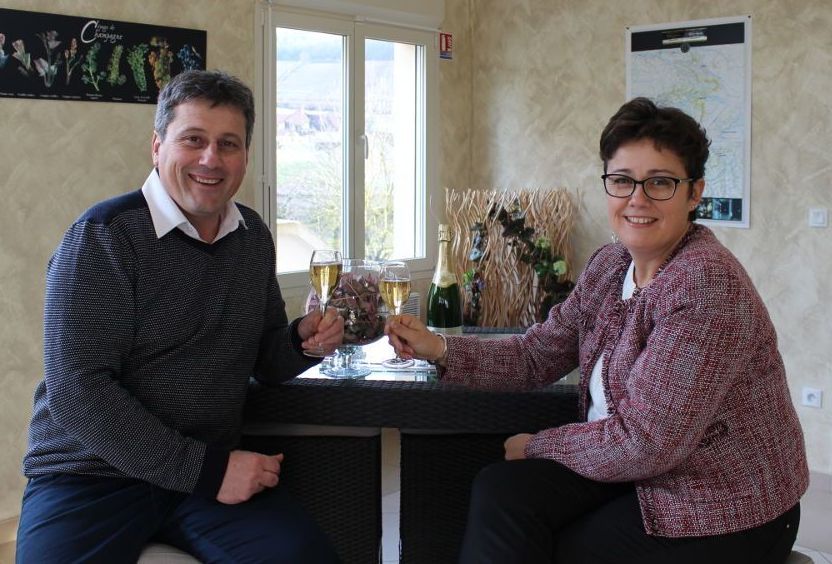 Un homme et une femme sont assis à une table et trinquent avec des coupes de champagne.