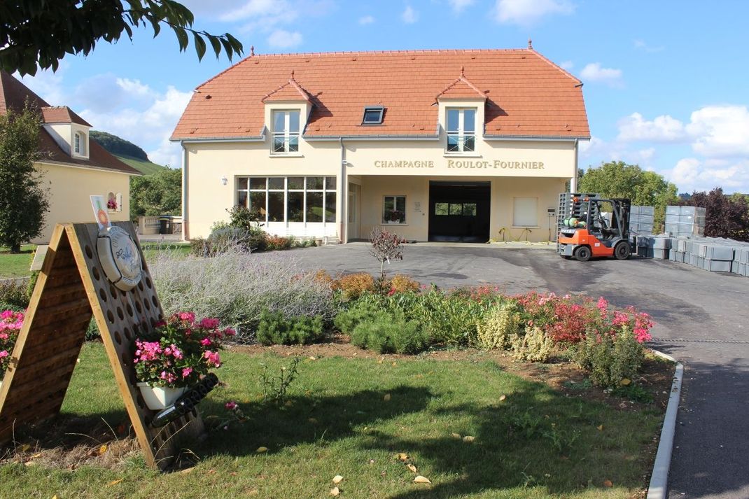 Un grand bâtiment avec un toit rouge et un chariot élévateur garé devant.
