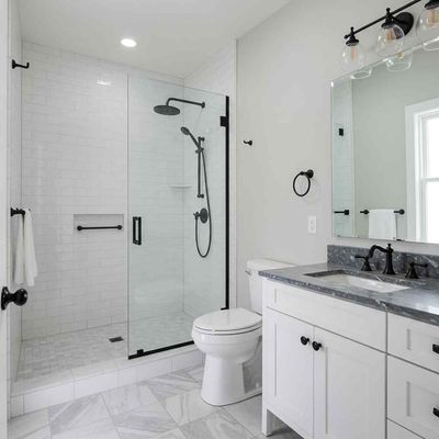 A bathroom with a toilet , sink , shower and mirror.