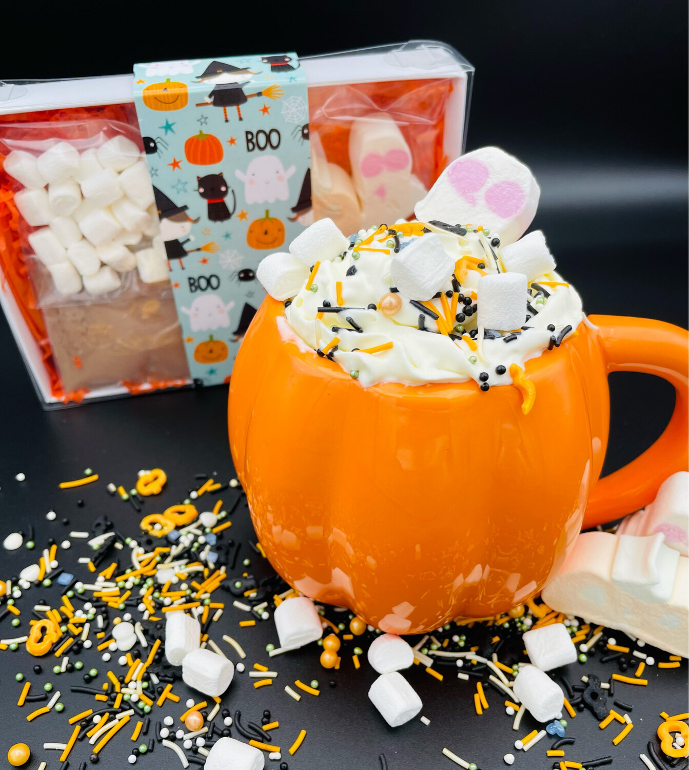 A mug in the shape of a pumpkin filled with whipped cream and marshmallows