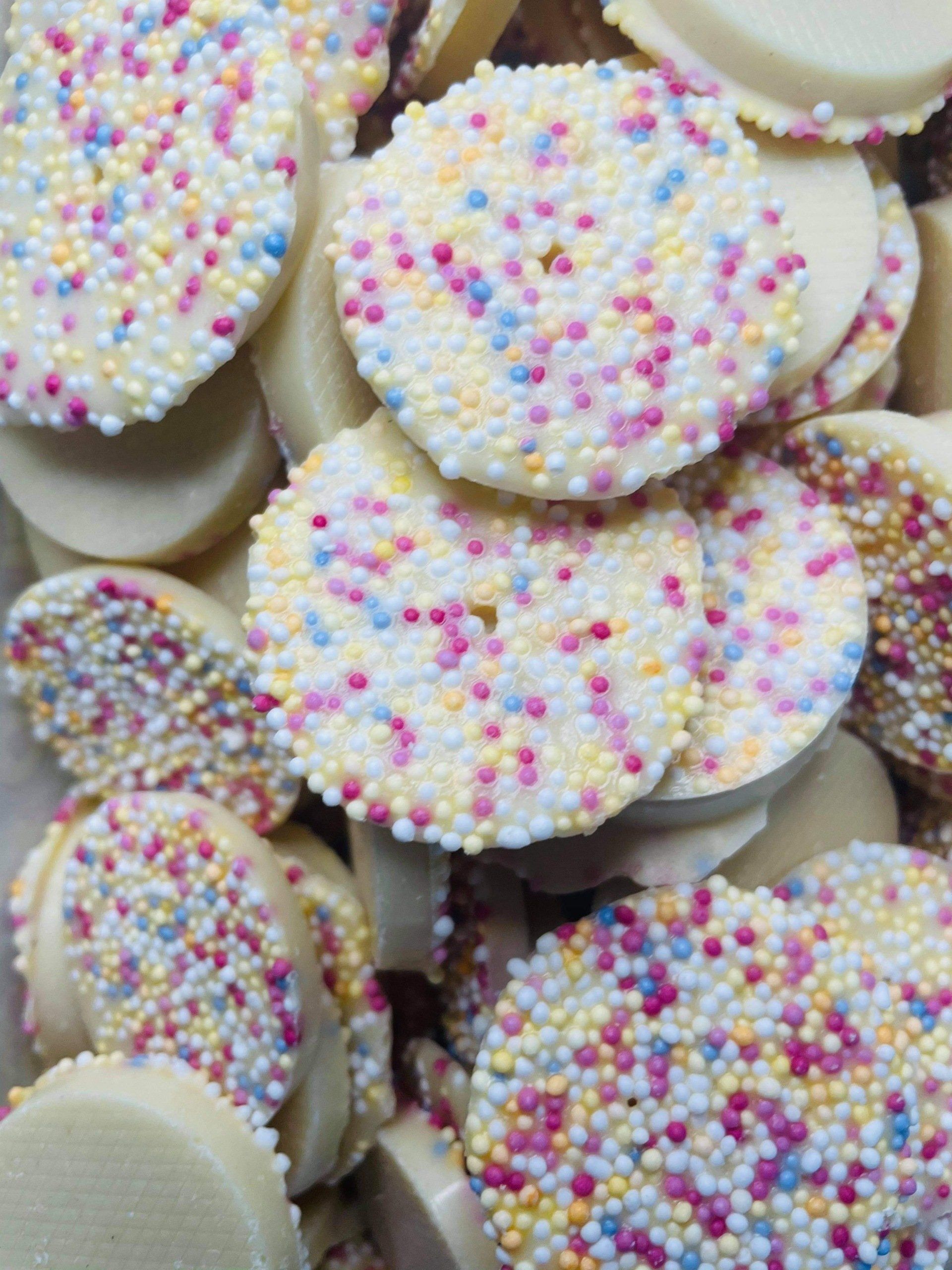 A pile of white chocolate covered cookies with sprinkles on them