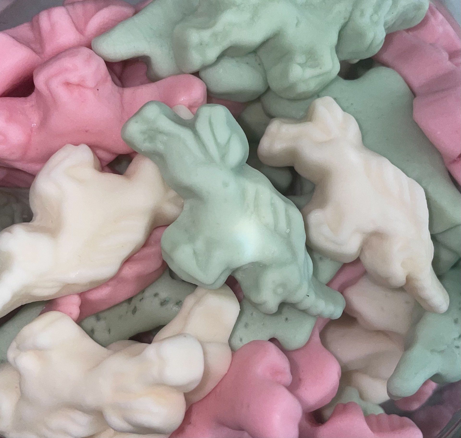 A pile of pink and green gummy dinosaurs