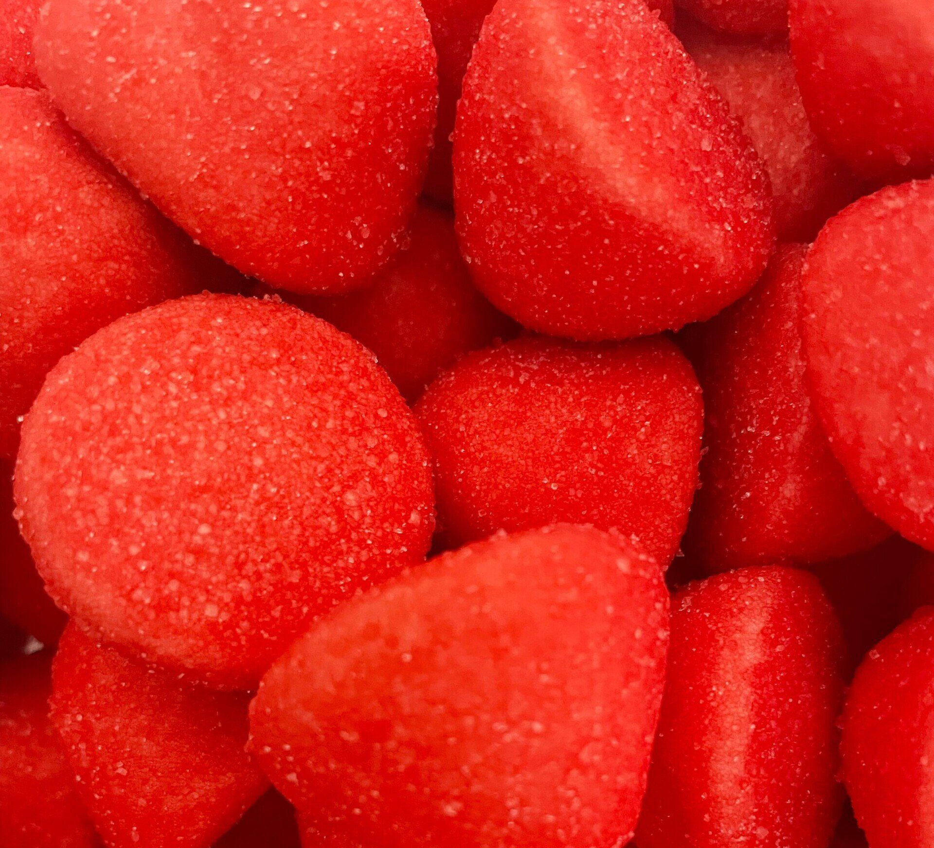 A close up of a pile of red candy that looks like strawberries.