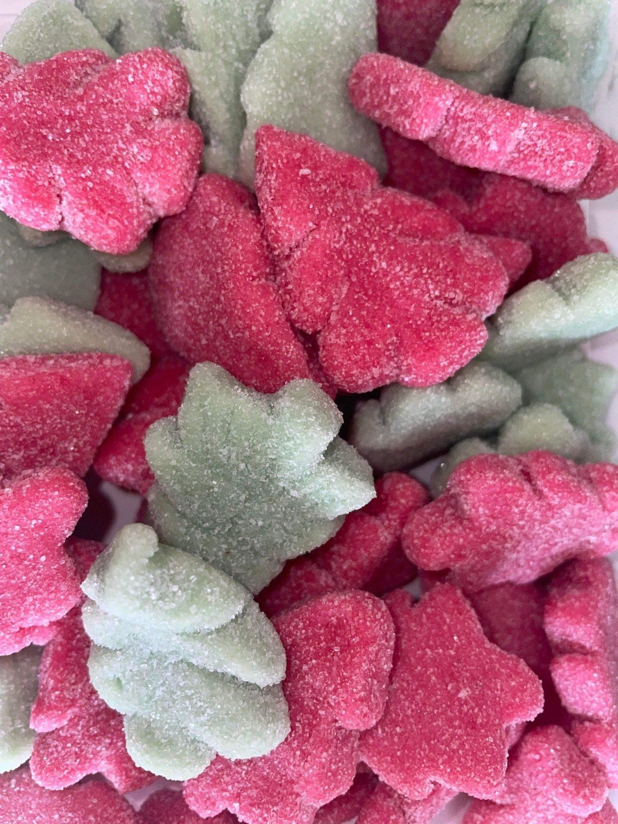 A pile of pink and green candy in the shape of trees and flowers.