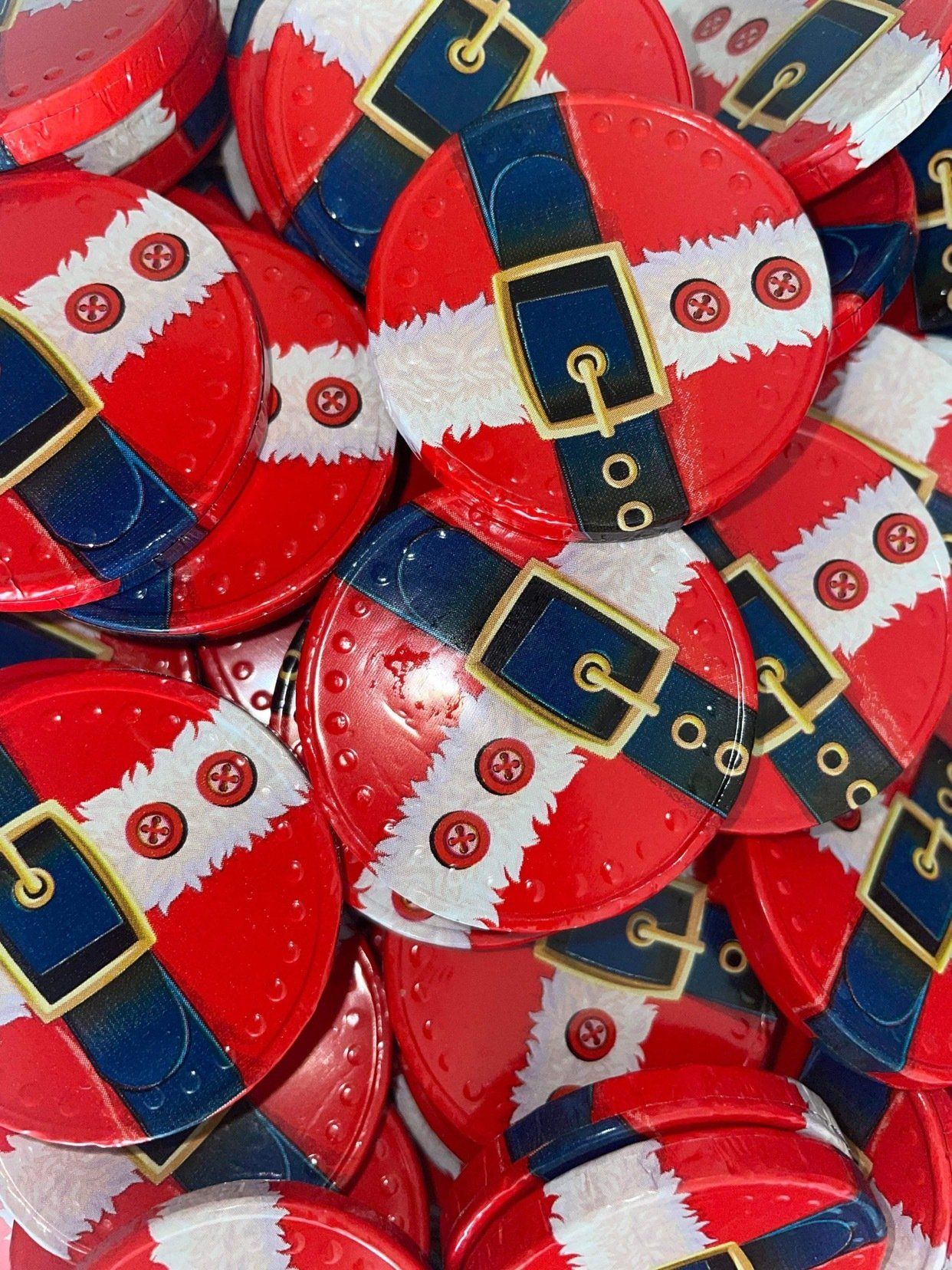 A pile of buttons with santa claus belts on them