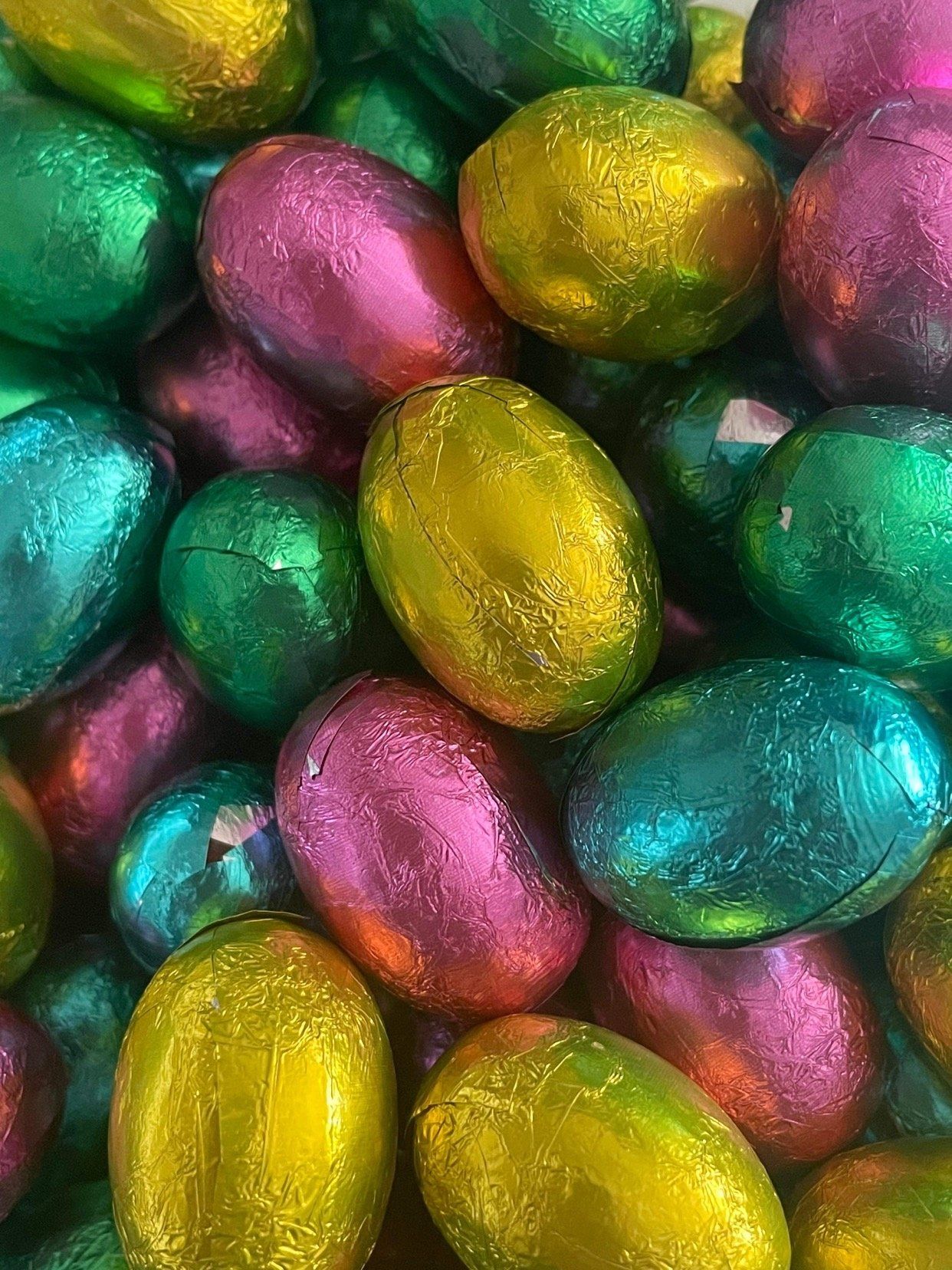 A pile of colorful chocolate easter eggs wrapped in foil.