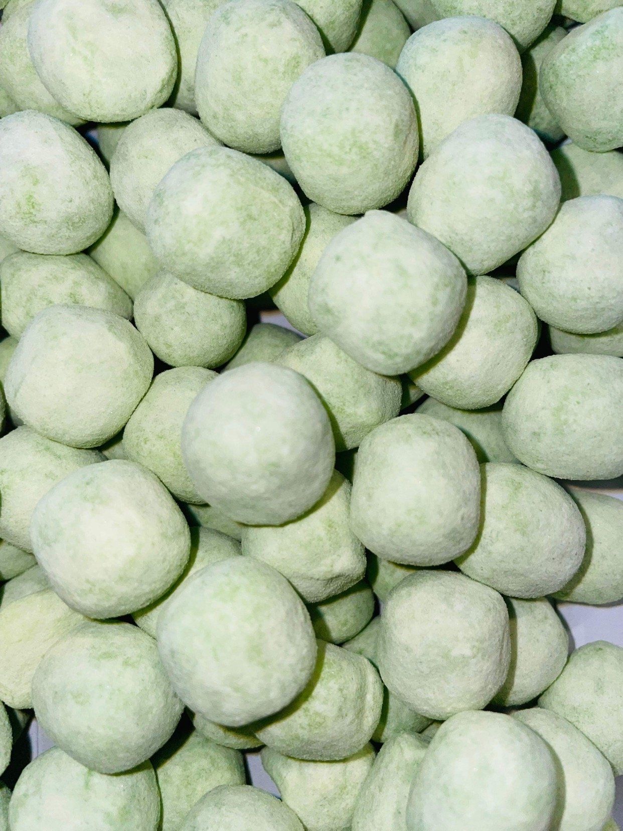 A pile of green balls are stacked on top of each other on a table.