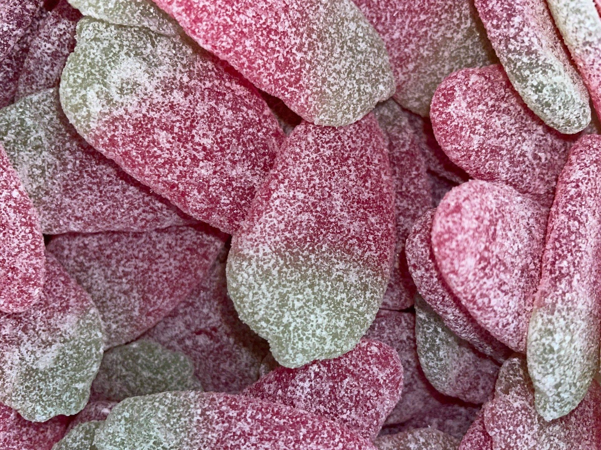 A close up of a pile of pink and green gummy candies.