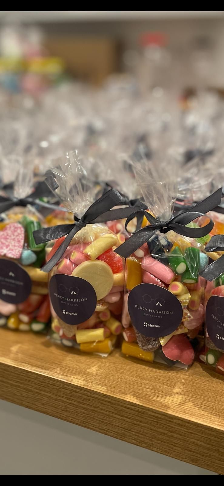 Bags of colorful candy tied with black ribbons, displayed on a wooden surface.