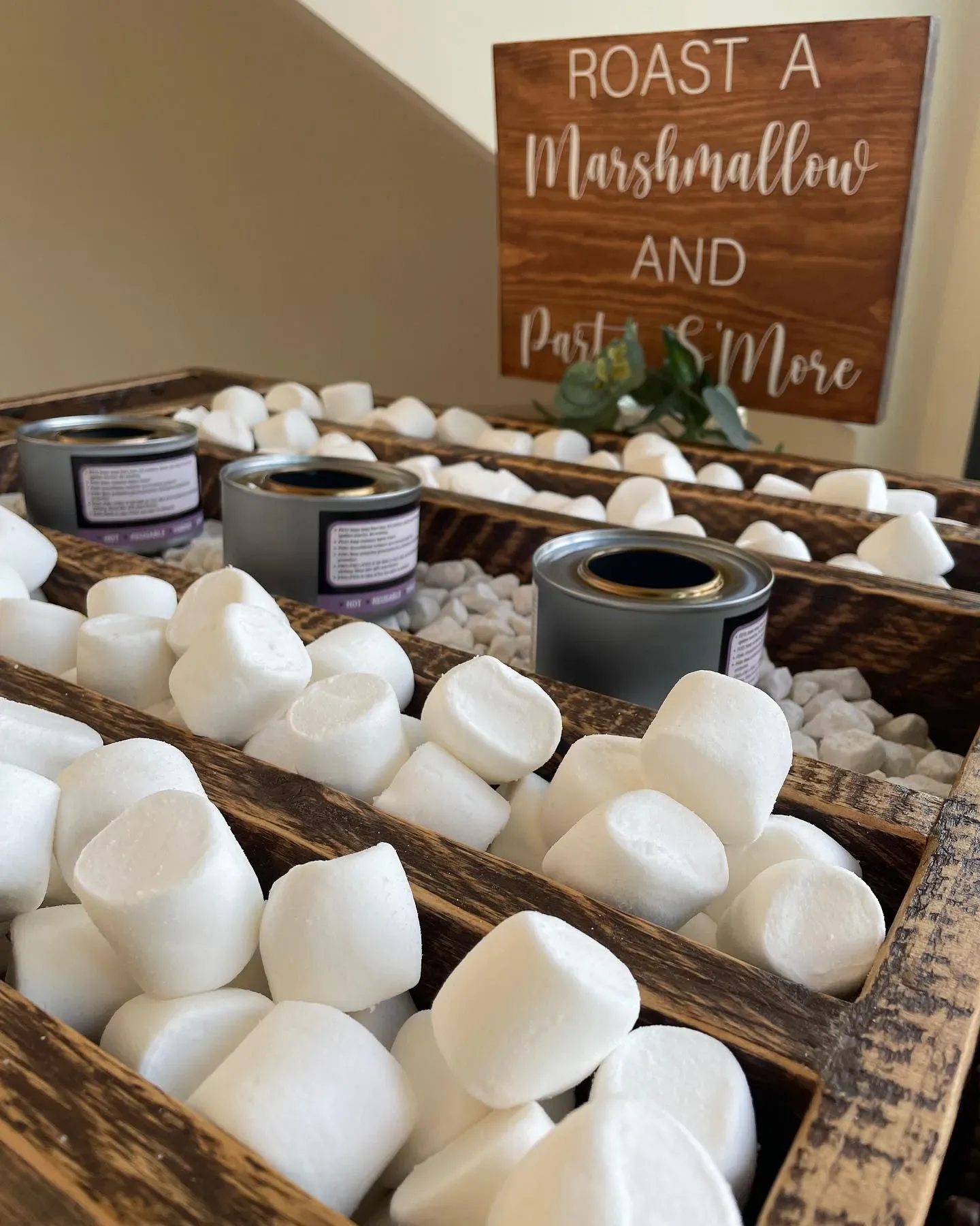 A wooden box filled with marshmallows next to a sign that says `` roast a marshmallow and party s more ''.