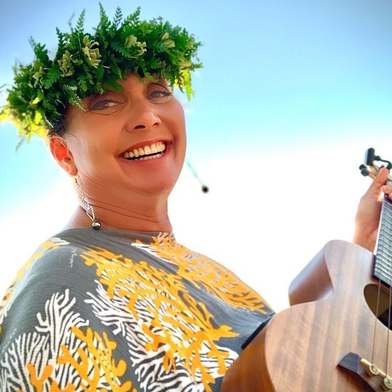 a woman wearing a lei is holding a guitar and smiling