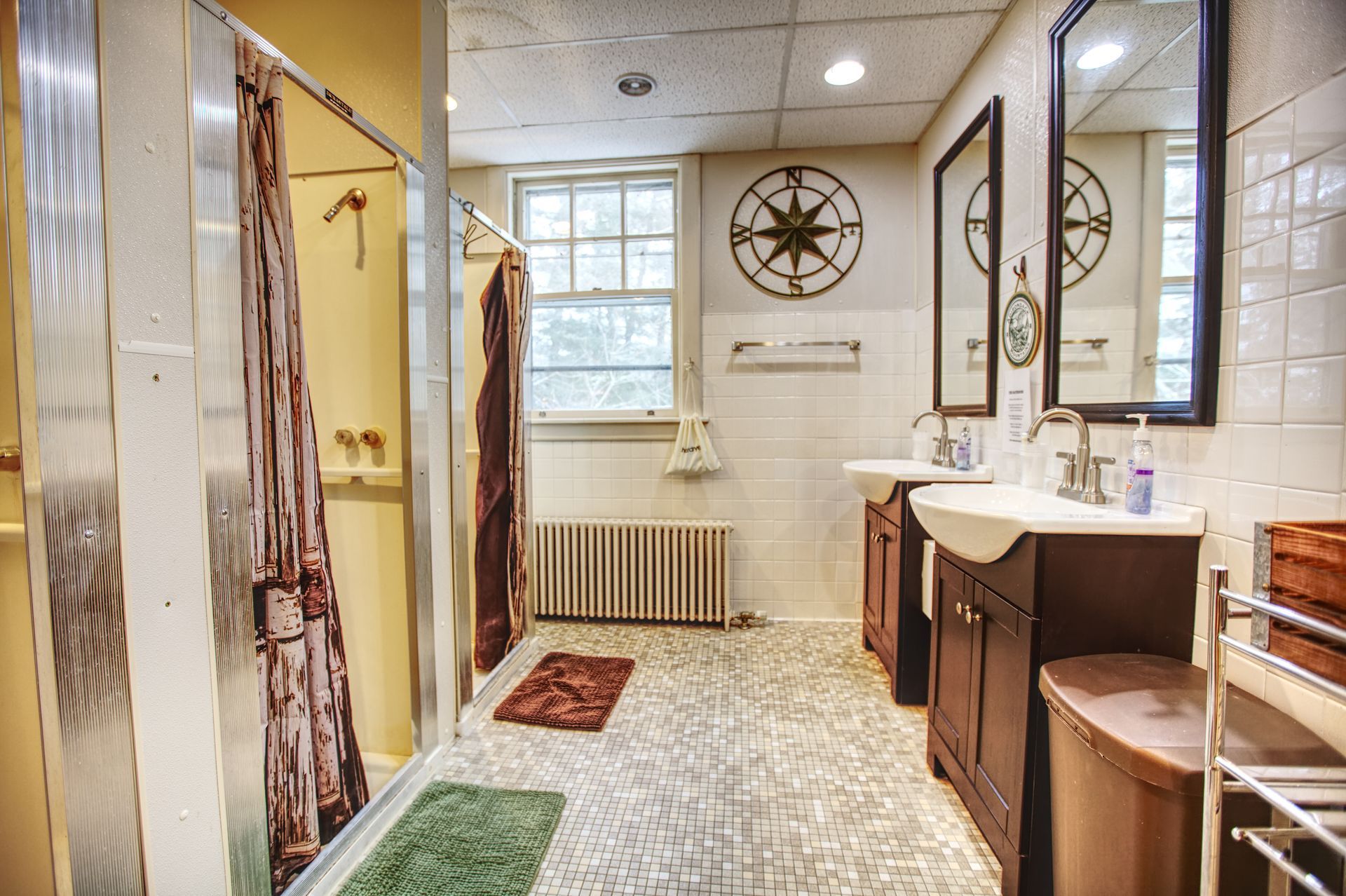 A bathroom with two sinks , a shower and two mirrors.