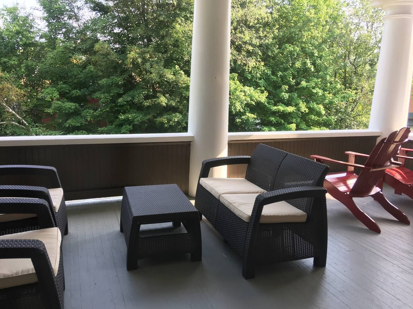 A porch with a couch , chairs and a table