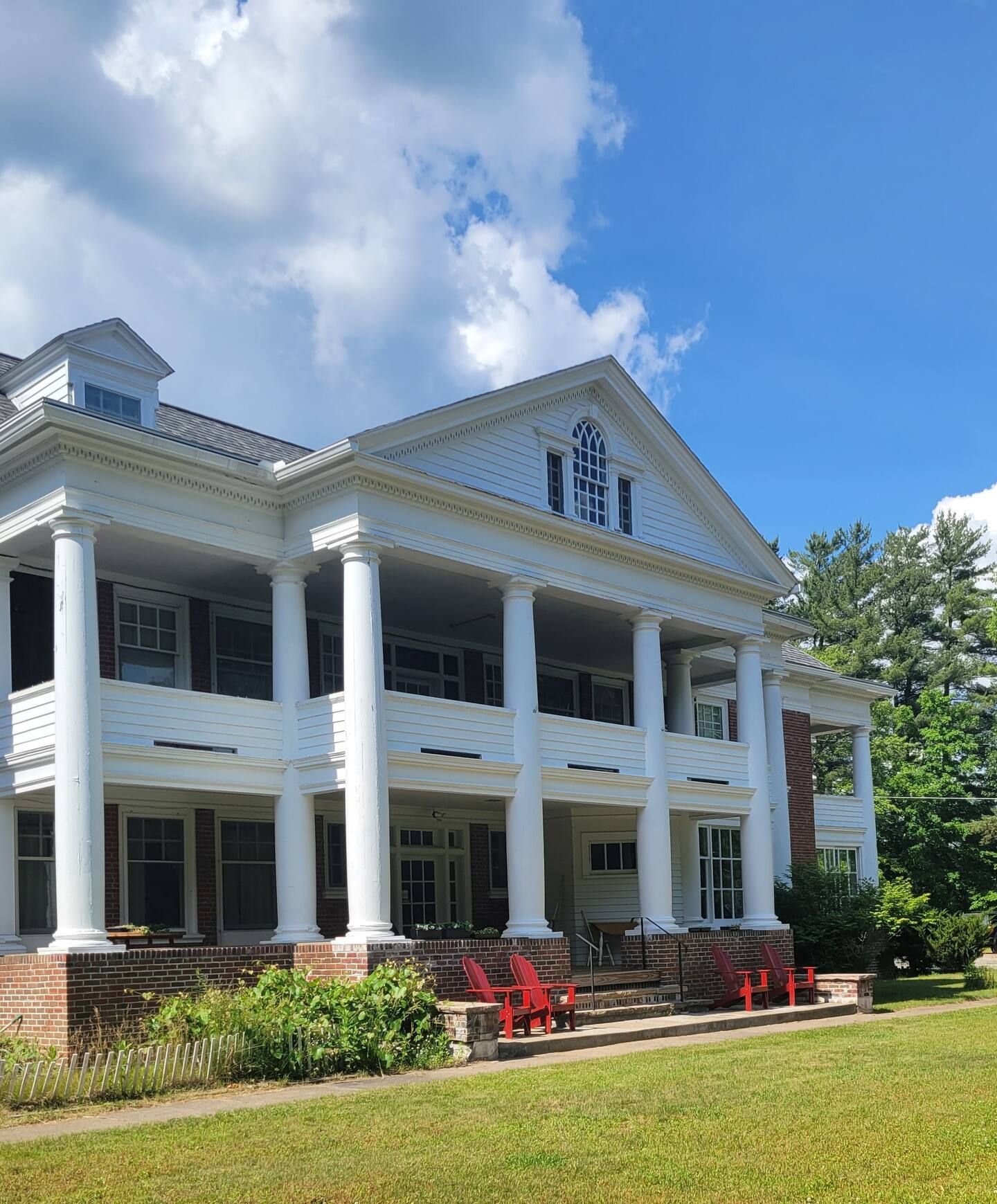 A large white house with red chairs in front of it