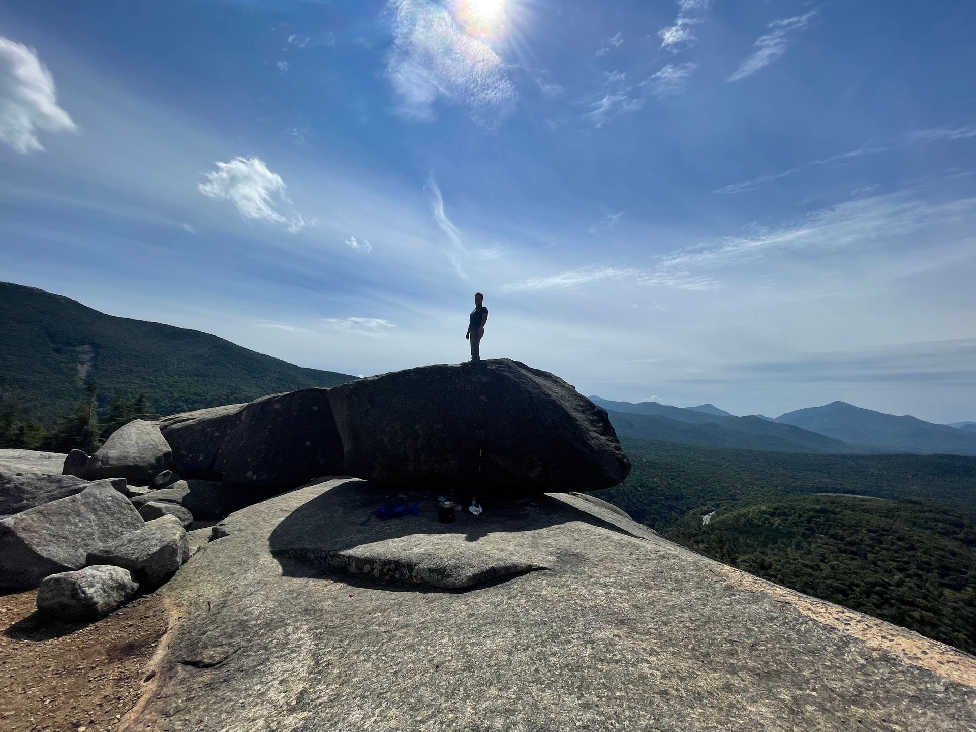 A person is standing on top of a large rock.