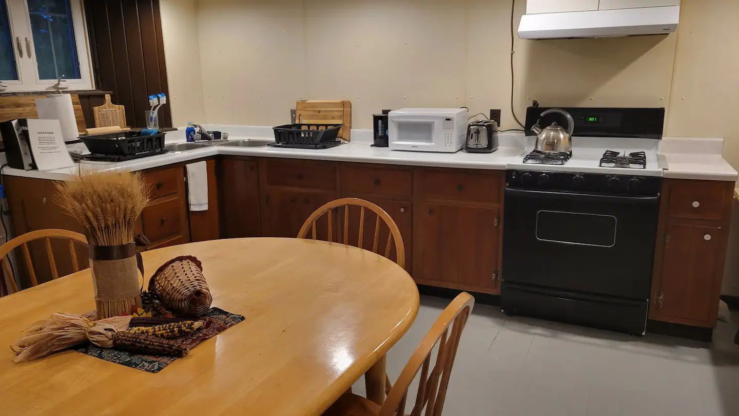 A kitchen with a table , chairs , stove and microwave.