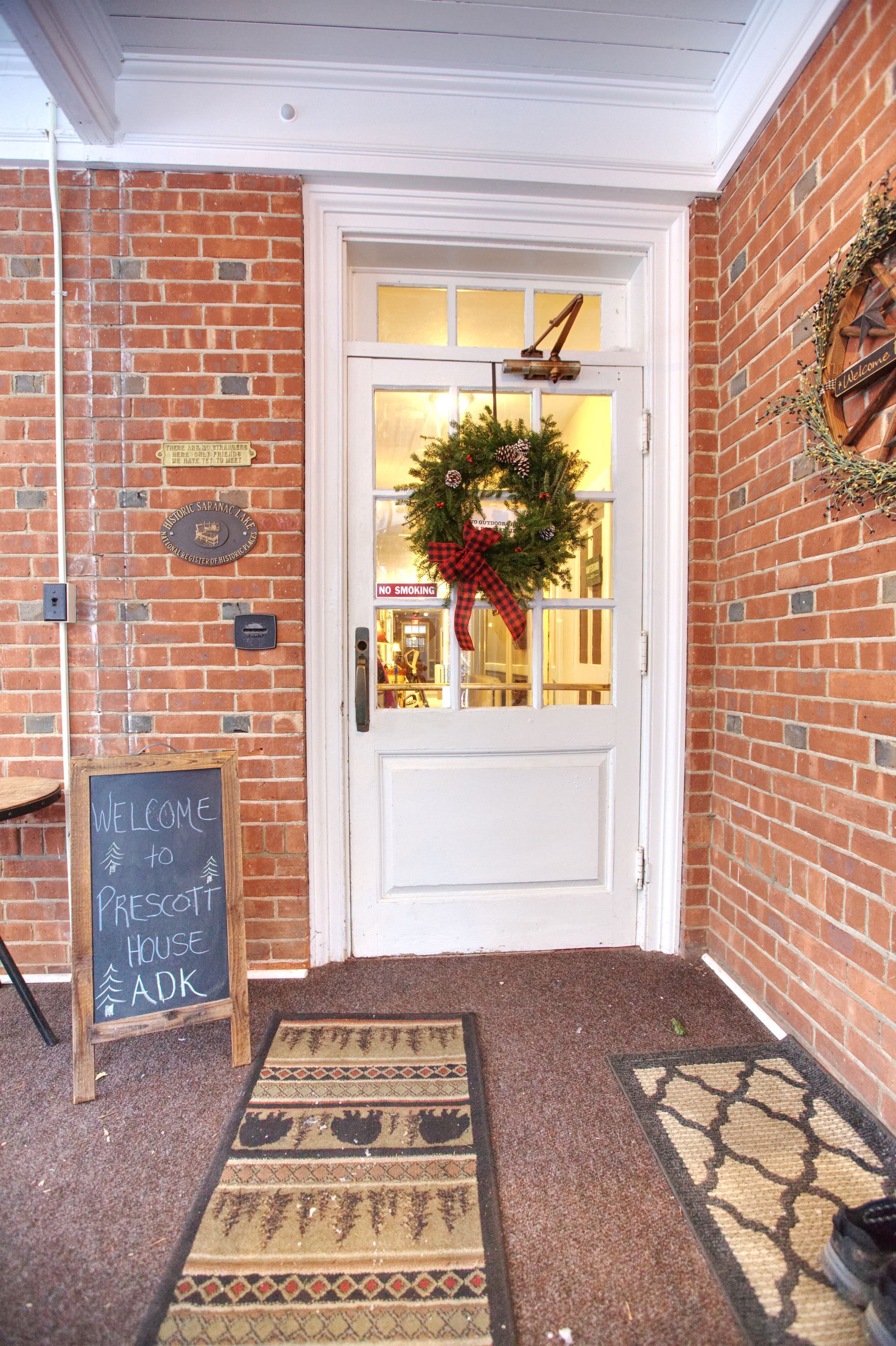 A brick wall with a white door and a christmas wreath on it.