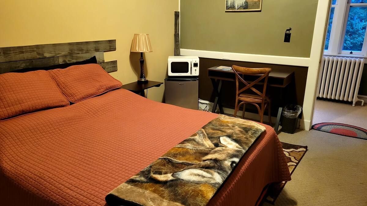 A bedroom with a bed , desk and microwave.